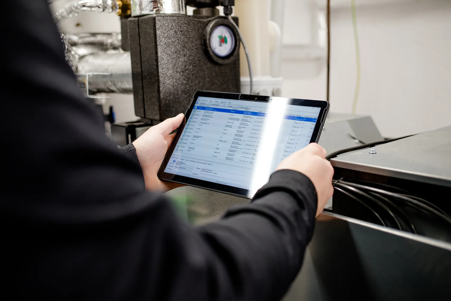 Techniker prüft eine Heizungsanlage mit Tablet